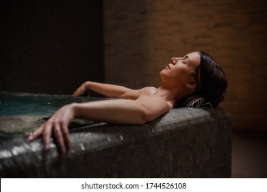 Conception of bodycare. Beauty and body care. View of a young woman enjoying whirlpool bath. Sensual young woman relaxing in spa hot tub.