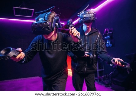 Conception of teamplay. Two young men in virtual reality glasses indoors.