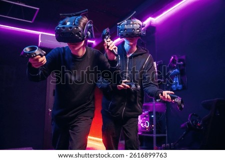 Conception of teamplay. Two young men in virtual reality glasses indoors.