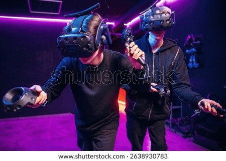Conception of teamplay. Two young men in virtual reality glasses indoors.