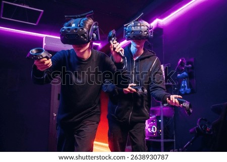 Conception of teamplay. Two young men in virtual reality glasses indoors.