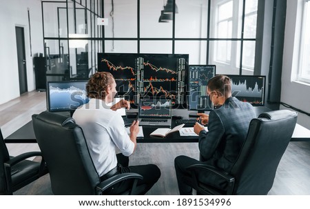 Conception of teamwork. Team of stockbrokers works in modern office with many display screens.