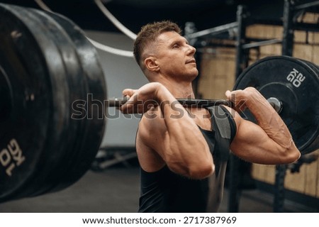Conception of weightlifting. Athletic man is doing exercise with a barbell in a gym.