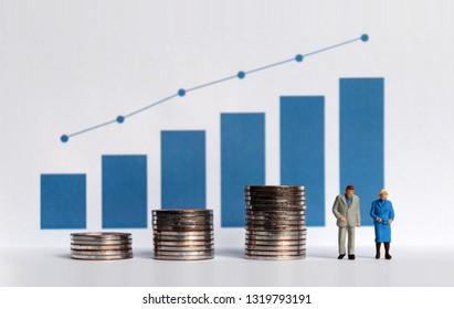 Concepts About Increasing Life Expectancy And Funding For Retirement. Blue Bar Graph With Flow Linear Graph. The Stack Of Coins And Miniature Older People.