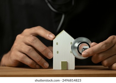 Concepts for checking health, real estate and investment. Wooden model house, hand hold stethoscope, on a wooden table. - Powered by Shutterstock