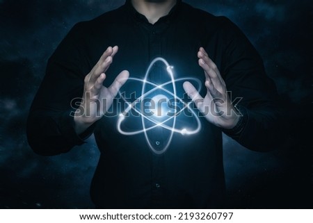 Concepts management peaceful atom. A man manipulates an atom on a dark background.