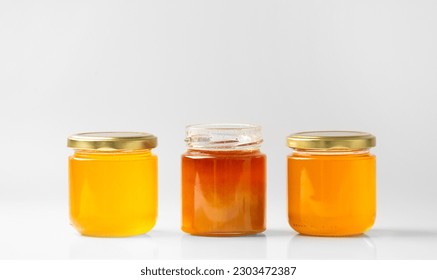 Conceptual composition of open and closed jars with different honey on isolation. Multi-colored honey in jars on a white background close-up. Honey of various types in glass jars. - Powered by Shutterstock