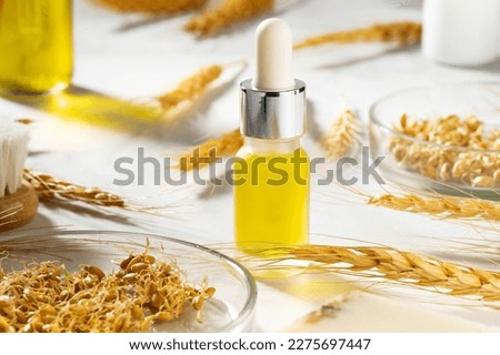 A conceptual composition of wheat essential oil, a bath brush and wheat germ on a marble table. Bottle of body oil with a dropper. Wheat serum oil for skin and hair care. Self-care, spa and wellness.