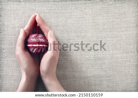 Conceptual and creative greeting card for independence day of  Latvia celebrations in 18 of November or 4 of May with hands holding a ball rolled up from Lielvarde belt and flag of Latvia ribbons