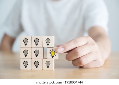 Conceptual of creative idea and innovation. Hand picked wooden cube block with light bulb icon - Shutterstock ID 1918034744