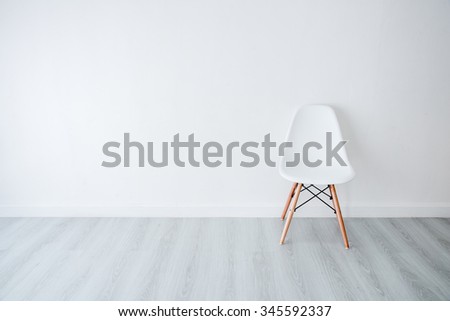 Conceptual Empty White Wooden Leg Chairs with white wall and gray wooden floor and copyspace