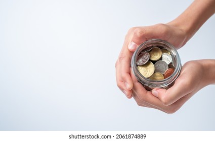 Conceptual Giving - Boy Holding out Jar of New Zealand Coins on White Background with Copy Space
