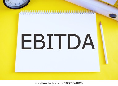 Conceptual hand writing showing Ebitda. Business photo text Earnings before tax is measured to evaluate company performance written in Notebook on yellow background