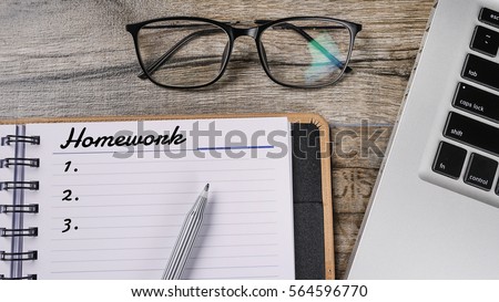 Conceptual of homework written on wooden table with notebook and spectacle