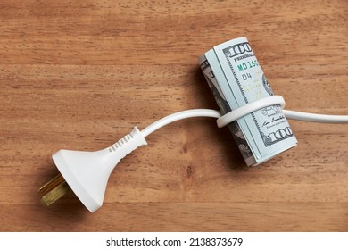 Conceptual Image About The High Economic Cost Of Electric Power And The Increase In Energy Rates: Power Cable Trapping A Roll Of Dollar Bills.