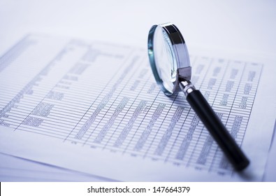conceptual image analysis of financial statements, documents and magnifier on an office desk