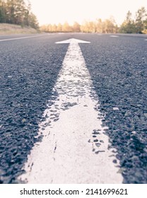 Conceptual image of an asphalt road and a direction arrow, the arrow on the road indicates the direction forward. dawn on the horizon.dawn on the way,