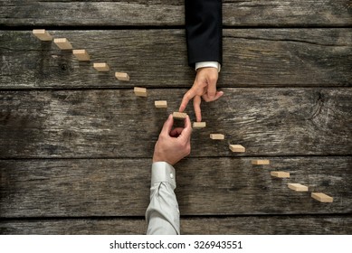Conceptual image of business partnership and support - businessman supporting wooden step in a staircase made of pegs as his partner walks his fingers up towards growth, achievement and development. - Shutterstock ID 326943551