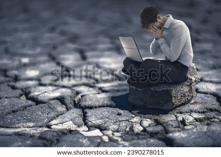 Conceptual image of a businessman holding his head, sitting on scorched earth