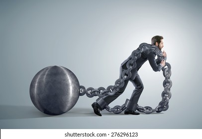 Conceptual image of a businessman pulling a heavy ball