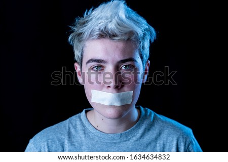 Conceptual image of censorship and social tabu of gender diversity concept.Transgender teenager with mouth sealed on tape not able to communicate or be free to express his own identity.