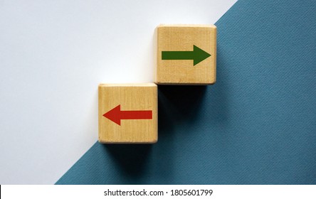 Conceptual image of choice and direction. Wooden cubes with arrows pointing in opposite directions. Beautiful white and blue background, copy space.