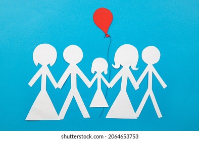 Conceptual Image Of Co Parenting. Two Families Sharing Custody And Parenting Together. Two Couples Sharing A Child With Red Balloon, Cut Out From Paper, Blue Background. Or Cluster Families Concept.