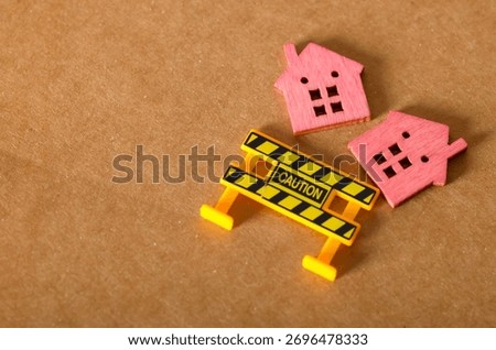 A conceptual image of a fallen model home with a warning barrier, representing a housing market crash or bubble.
