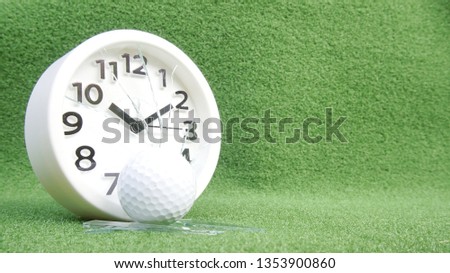 Conceptual image of golf as a time consuming sports. Broken glass of a clock and golf ball on green grass.