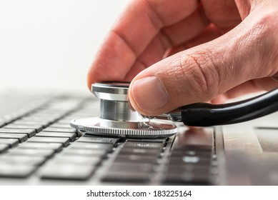 Conceptual image of the hand of a man checking the health of his laptop computer using a stethoscope as he checks for malware and viruses or any electronic malfunctions.