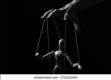 Conceptual image of a hand with strings on fingers to control a marionette in monochrome