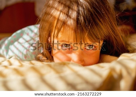 Conceptual image: happiness, carelessness and a sense of absolute safety. Young child girl wake up in sun rays. 