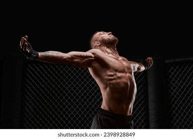 Conceptual image of a kickboxer. A real fighter stands in the real cage of the octagon. The concept of mixed martial arts, kickboxing, sports schools. Mixed media