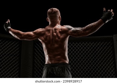 Conceptual image of a kickboxer. A real fighter stands in the real cage of the octagon. The concept of mixed martial arts, kickboxing, sports schools. Mixed media - Powered by Shutterstock