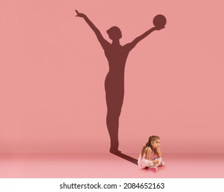 Conceptual Image With Kid, Little Girl And Shadow Of Female Gymnast On Studio Pink Wall. Dreams About Sport Career. Achievements, Childhood, Dreams, Imagination, Education Concept.