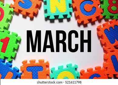 A Conceptual Image Of Kids Puzzle Foam On A White Background And A Word Month Of MARCH
