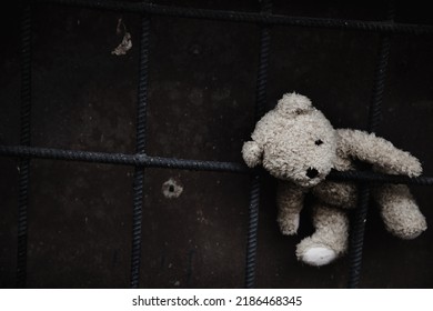 Conceptual image: lost childhood, loneliness, pain and depression. Dirty toy Teddy bear lying down outdoors. Copy space.
