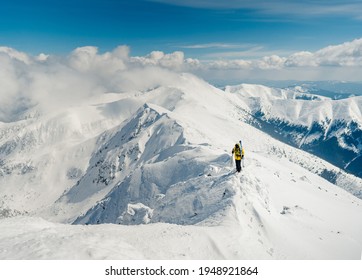 Conceptual image of a man hiker with backpack in front of a mountain. Sports man or skier walks in the mountains. Hiker with backpack standing on top of a mountain and enjoying view. Adventure