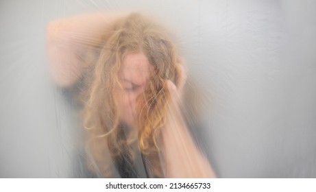 Conceptual Image Of A Mature Woman Grabbing Her Head From A Headache, The Position Behind Transparent Plastic Film Represents The Altered Perception And The Dull Pain, Copy Space