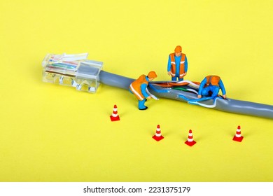 Conceptual image of miniature figure workmen investigating a fault on a broadband network cable - Powered by Shutterstock