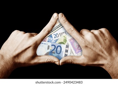 Conceptual image of money worship. Fingers arranged in a triangle with banknotes inside. Evoking symbolism of wealth and the enigmatic allure of the Illuminati. Triangle gesture. Money rules the world
