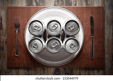 Conceptual image representing alcoholism on a funny way using a six-pack of beer cans for dinner.
