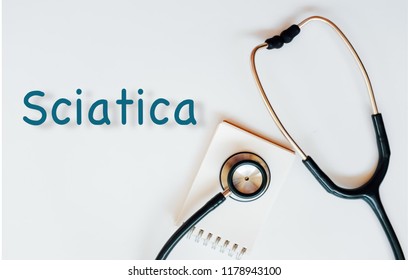 Conceptual image with Sciatica inscription with the view of stethoscope and notebook on the white background. Medical Conceptual. Copy space.