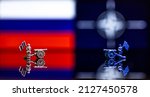 Conceptual image of war between Russia and NATO using toy soldiers and national flags on a reflective background