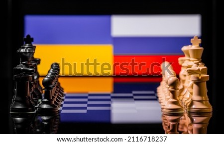 Conceptual image of war between Russia and Ukraine using chess pieces and national flags on a reflective background