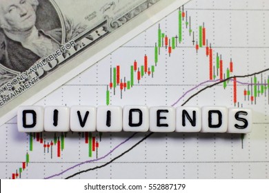 Conceptual image of the word dividend on letter cube with stock graph and dollar background.