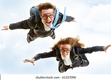 Conceptual image of young business partners flying with parachutes on their backs
