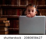 Conceptual mage: The largest  library is a digital library.  Portrait of young beautiful girl sitting in library and learning with laptop. Copy space. Horizontal image.