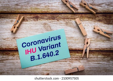 Conceptual message card showing Coronavirus IHU Variant B.1.640.2 with wooden clothespin or natural wooden pinch on shabby wooden table. New COVID-19 variant detected in southern France.