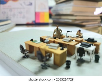 Conceptual miniature photo scene of worker on the office table with unfocus book and blurred stationery stuff. - Shutterstock ID 2065214729